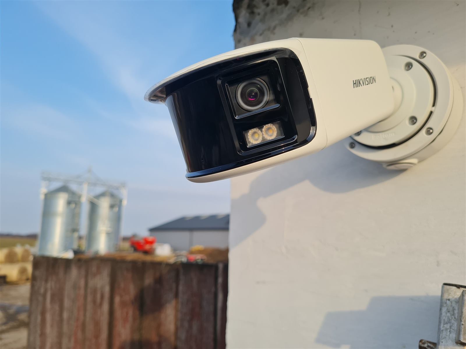 Kamera monitoringu na budynku gospodarstwa rolnego, w tle silosy